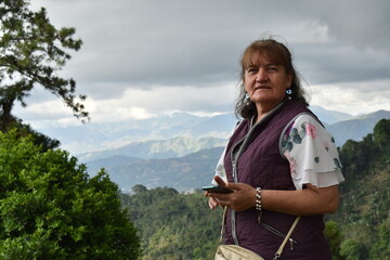 MUJER MAYOR EN PAISAJE DE NUBES AZULES EN LA MONTAÑA 