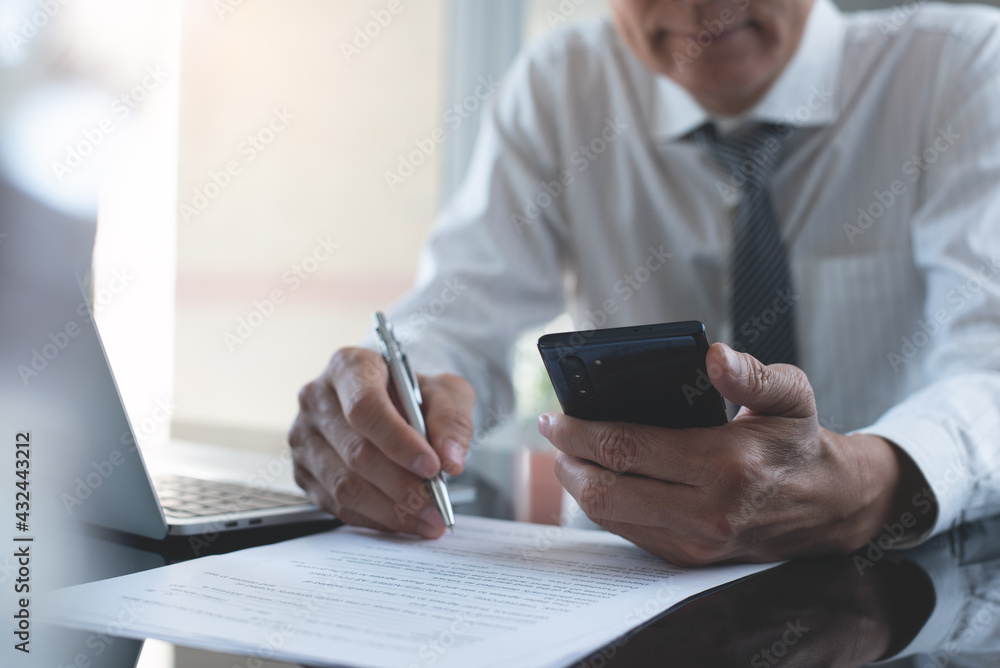 Poster business man using mobile smart phone reading information with paper document and laptop computer on