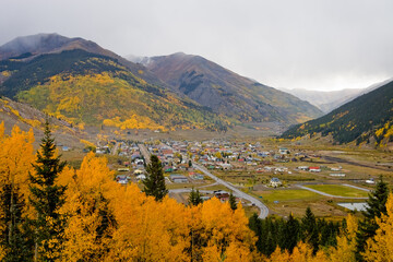Silverton Colorado surrounded by gold and orange autumn leafed aspen trees on a foggy fall day in San Juan County, Colorado