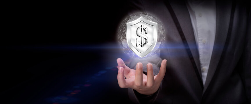 Businessman holding a shield with Currency sign on dark background, Concept of secure financial network, protection money.