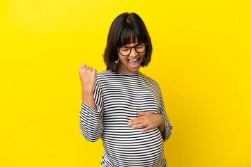 Young pregnant woman over isolated yellow background celebrating a victory