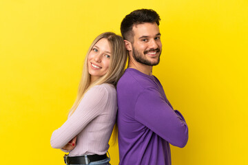 Obraz premium Young couple over isolated yellow background keeping arms crossed