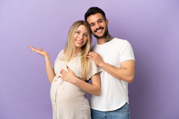 Fototapeta premium Young couple pregnant and presenting something