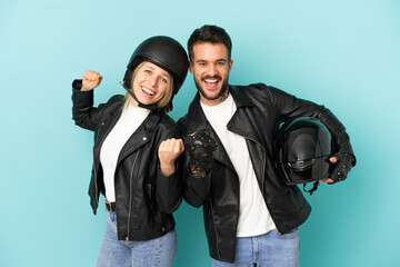 Couple with motorcycle helmet over isolated blue background celebrating a victory