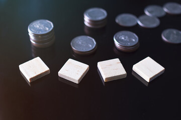 Square wooden on black glass with blur image of stack cash coin money background. for add text happy new year 2022. planing earn money finance investment and saving money future for 2022 new year.