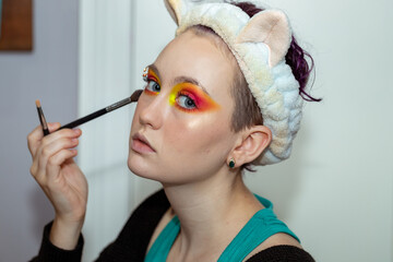 Young woman glances at camera while applying makeup