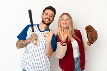 Couple playing baseball over isolated white background showing an ok sign with fingers