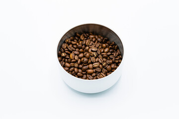 Mixture of different kinds of roasted coffee beans in white container on white background. Copy space.