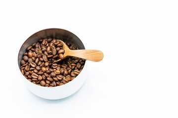 Mixture of different kinds of roasted coffee beans with wooden spoon in white container on white background. Copy space.