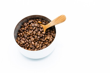 Mixture of different kinds of roasted coffee beans with wooden spoon in white container on white background. Copy space.