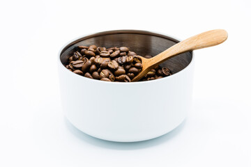 Mixture of different kinds of roasted coffee beans with wooden spoon in white container on white background. Copy space.