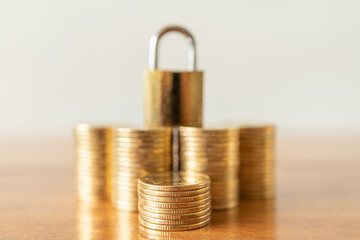 Money and Security Concept. Closeup of stack of gold coins with golden master key lock on top as...
