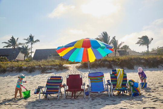 Beach chairs under colorful sun umbrella all set up for the first day of a wonderful beach vacation