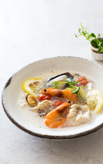 Bowl of soup with cod, mussels, shrimps and coconut milk close up