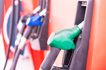 Close up green fuel nozzle on tank of gas station in commercial gas station to filling power oil energy into car for transportation without copy space in frame