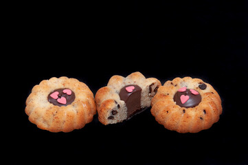 Three cookies with chocolate in the middle and hearts, on black background
