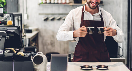 Portrait of barista man small business owner holding cup of coffee in the cafe or coffee shop.Male barista standing at cafe