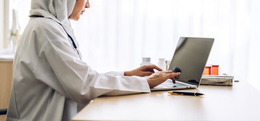 Muslim asian woman doctor and stethoscope working with laptop computer in hospital.healthcare and medicine