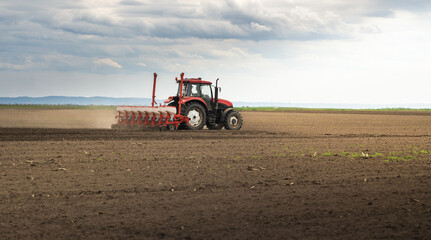 Obraz premium Farmer with tractor seeding crops at field
