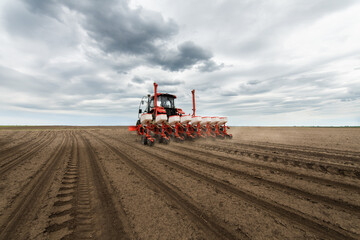 Obraz premium Farmer with tractor seeding crops at field