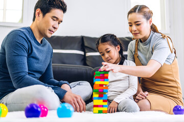 Portrait of enjoy happy love asian family father and mother with little asian girl smiling playing with toy build wooden block board game in moments good time at home