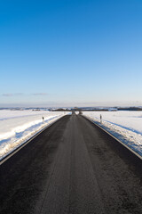Beautiful road between snow with nice blue sky 