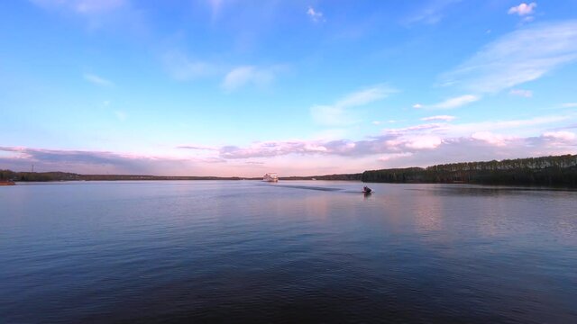 Timelapse passage of a large passenger ship along the river at sunset. Beautiful colorful landscape of the river against the background of the blue sky at sunset
