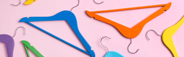 Creative flat lay multicolor wooden hangers at pink pastel background