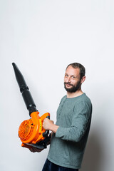 The worker holds a blower in his hands, isolated on white. Man on a studio with a leaf blower....