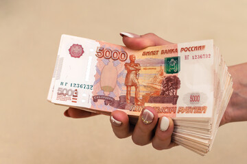Woman hands holding stack of five-thousand russian ruble banknotes