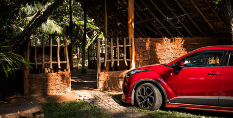 Thatched village house and a modern car parked near the entrance door.
