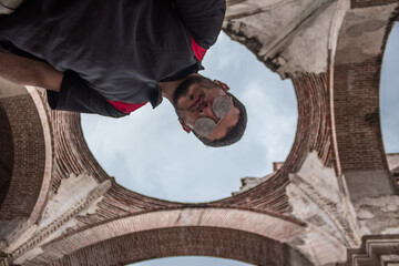 backsplash view of adult man in black shirt and glasses in the ruins of a cathedral in a classic...
