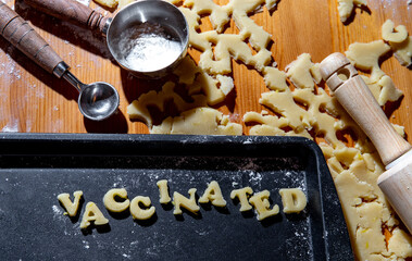 Plaque à biscuit avec écriture en anglais avec de la pâte à biscuit fraichement préparée en forme de lettre avec un mot qui indique vacciné - Powered by Adobe