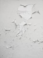White paint is cracking on the old wall