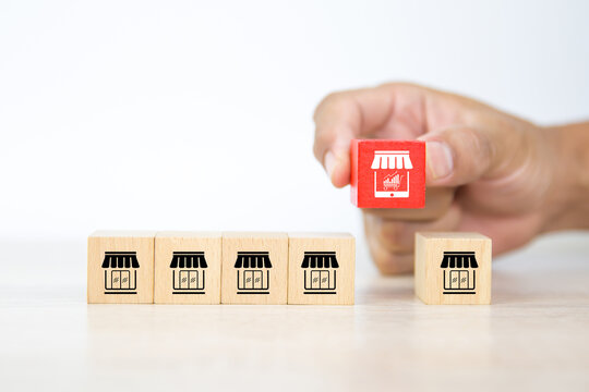 Franchise, Close-up hand choosing cube wooden blocks stack with franchise business store E-commerce smartphone icon. for business growth and change to online financial marketing concepts.