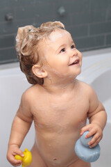 Cute funny baby boy enjoying bath and bathed in the bathroom.