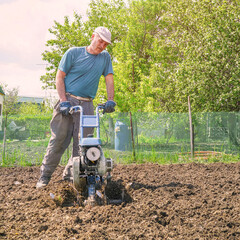 Man cultivates the soil in the garden using a motor cultivator - tiller