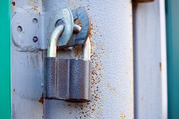 Сlosed padlock hanging on the hinges