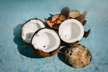 Coconut halves, coconut pieces on a blue background. background with split coconuts close-up. Piece of spoiled coconut, blurred background.