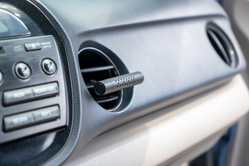 Air freshener in car vent,black interior, close up. Car air freshener mounted to ventilation panel,...