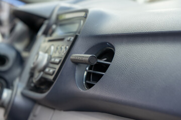 Air freshener in car vent,black interior, close up. Car air freshener mounted to ventilation panel, fresh flower scent