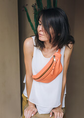 Caucasian woman 30 years old in white blouse wears orange banana bag. Leather Sling Purse Bum Bag.