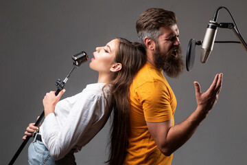 Couple singing. Singing man and girl in a recording studio. Expressive couple with microphone....
