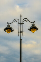 city lit light pole on day with cloudy sky