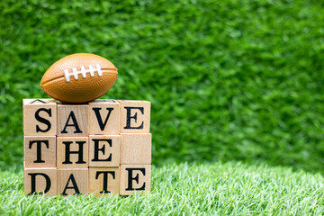 American football with Save the date on green grass background