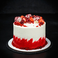 The birthday cake is decorated with strawberries and red velvet on a black background