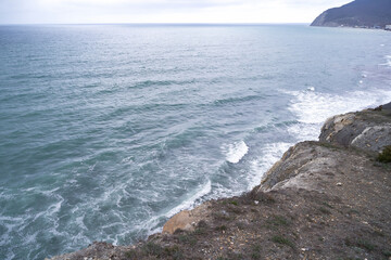The sunrise over the calm sea casts rays of orange light into the air as the setting sun penetrates through the clouds into the picturesque calm seascape