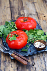 grandes tomates vermelhos maduros com salada de agrião e sal do mar estão em uma bandeja - uma excelente opção para uma dieta saudável.