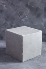 Concrete cube or construction brick near wall background texture. Abstract art or construction concept