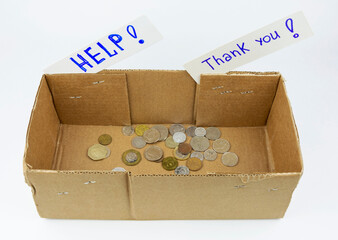 A cardboard donation box with coins and the inscription help on a white background. The request of...